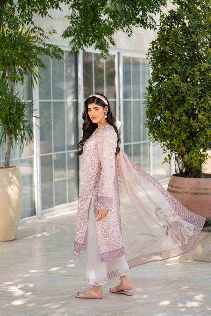 Woman in blush pink embroidered 3-piece suit with white trousers and chiffon dupatta, walking outdoors in modern ethnic summer style