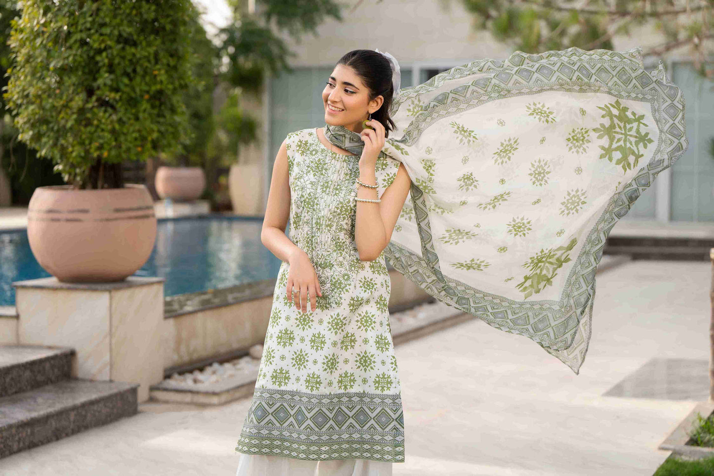 A formal Pakistani dress featuring intricate embroidery on lawn, paired with a classic cotton trouser and chiffon dupatta