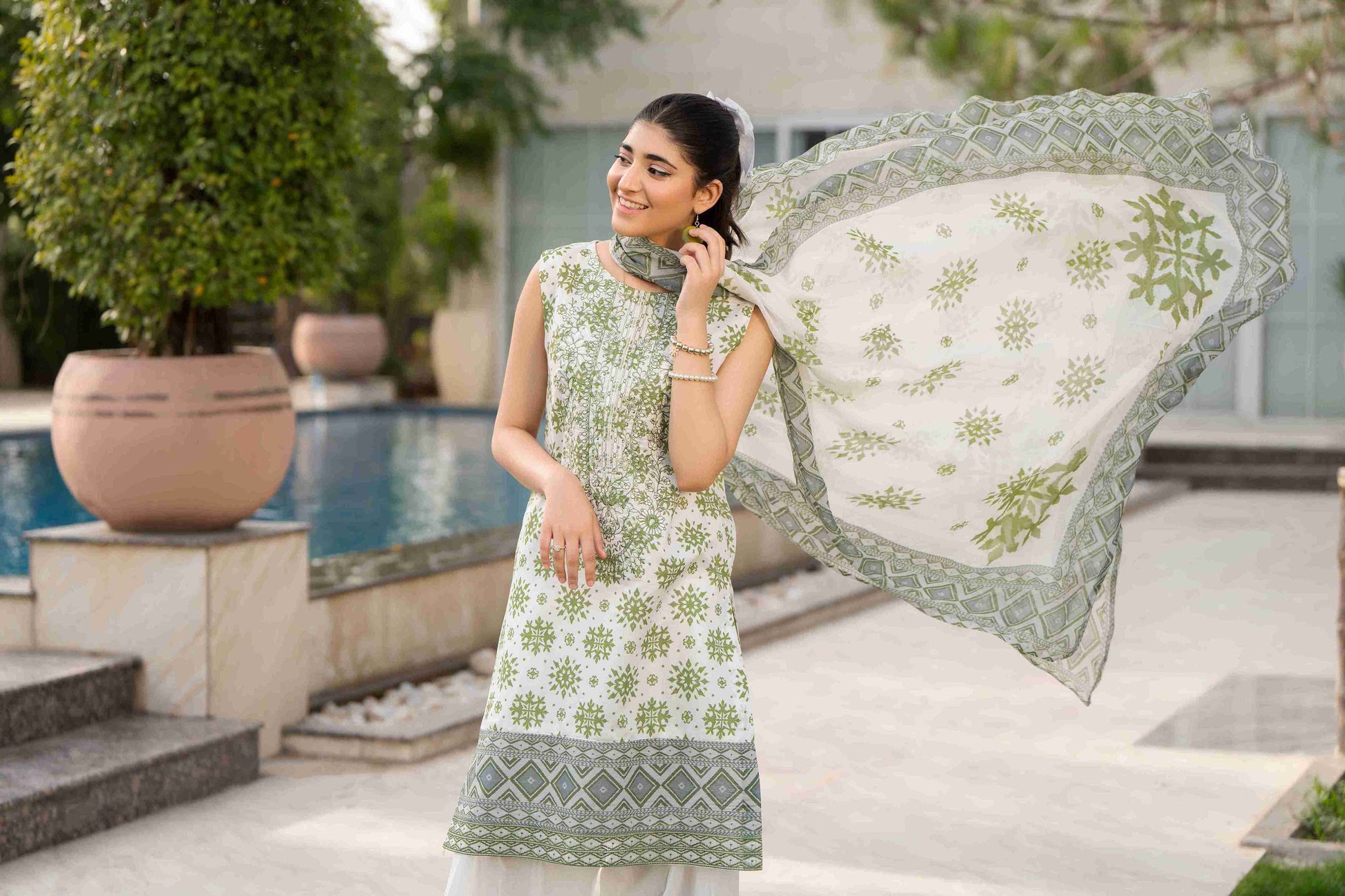 A formal Pakistani dress featuring intricate embroidery on lawn, paired with a classic cotton trouser and chiffon dupatta