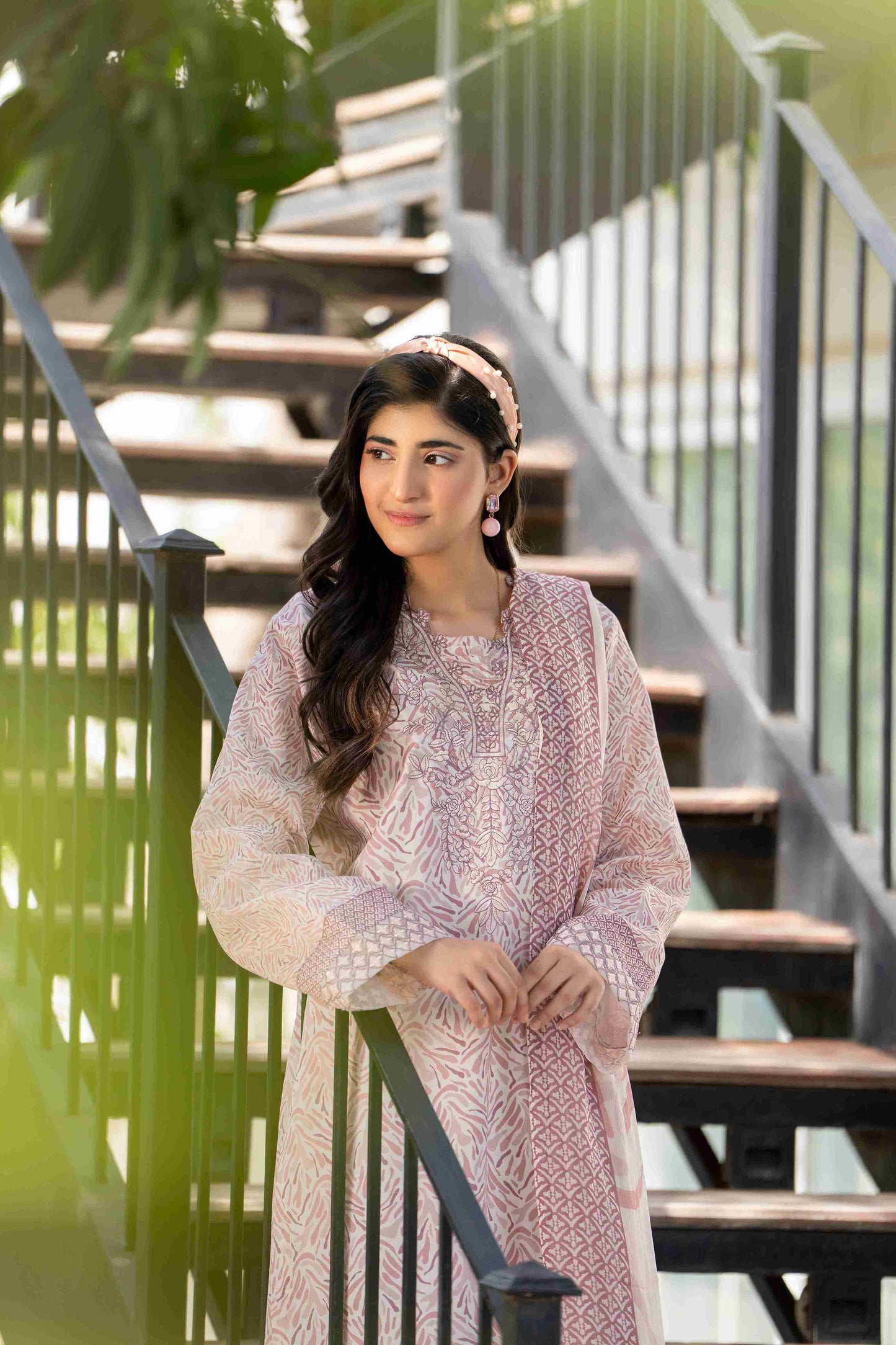 Woman wearing a refined blush pink embroidered kurta with delicate patterns, standing by a staircase in natural daylight - showcasing elegant and modern ethnic fashion